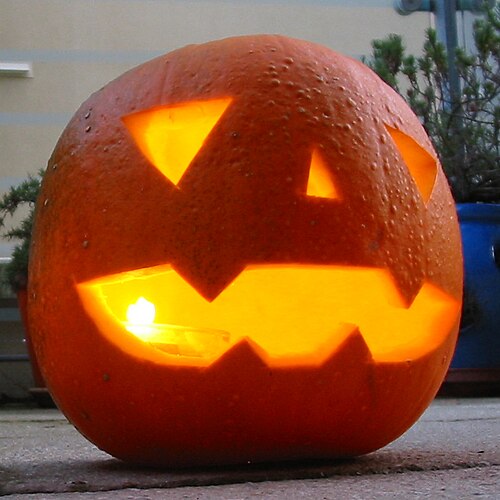 Calabaza de Halloween iluminada con cara tallada, mostrando una expresión divertida.